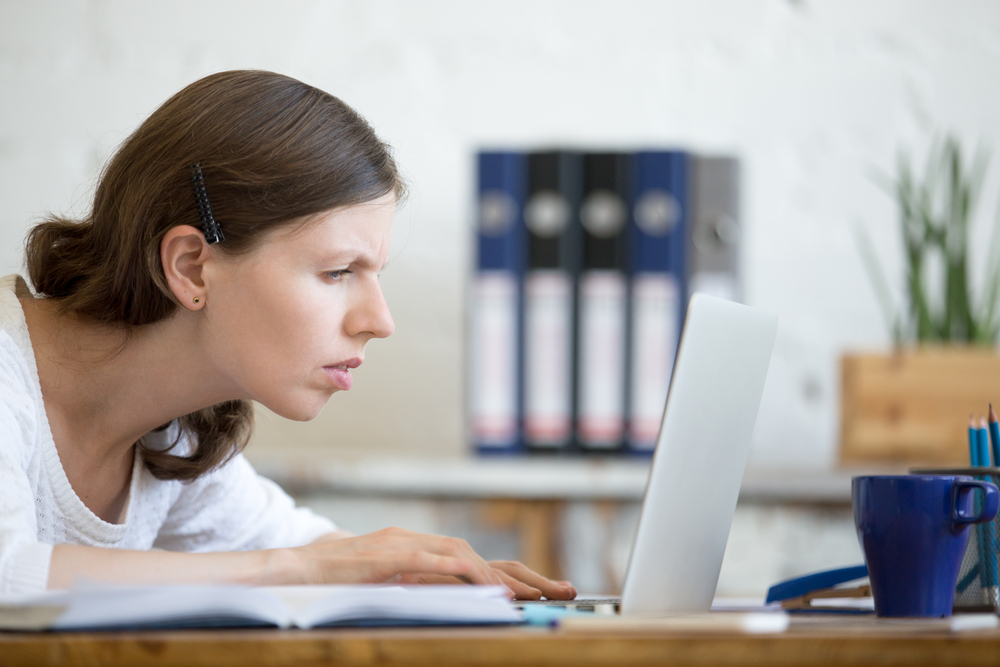 Young,Stressed,Businesswoman,Sitting,With,Laptop,And,Looking,At,Screen