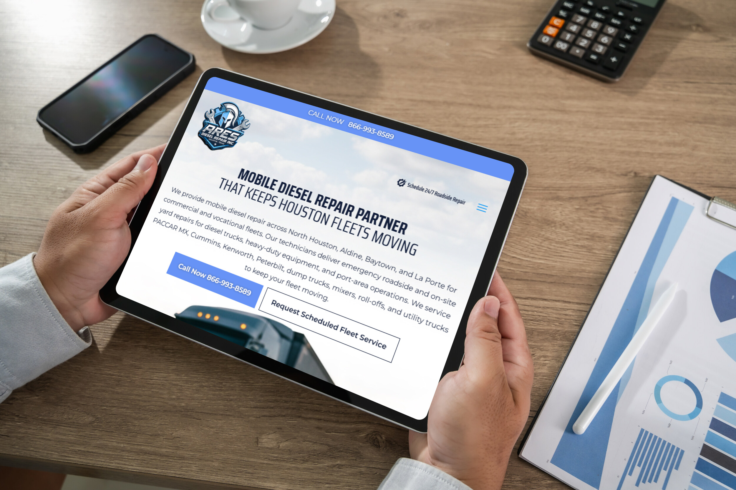 Manholdsamockuptabletblankscreenmockupforux | itvibes full service digital marketing agency in houston Person Viewing a Tablet Displaying a Diesel Repair Company Website on a Desk with a Phone Cup and Calculator Nearby