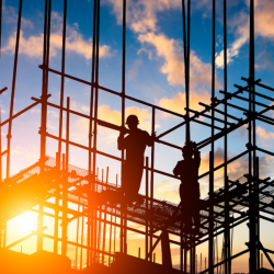 Construction workers on a construction site with the sun setting