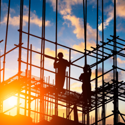 Construction workers on a construction site with the sun setting